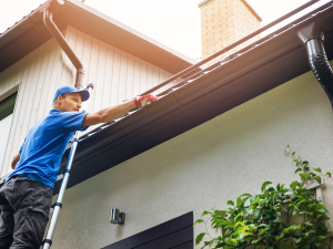 Professional roofer in Columbia cleaning gutters to prevent ice dams