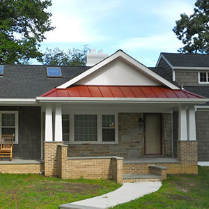 Front view of a residential home with a red metal roof over it's front porch